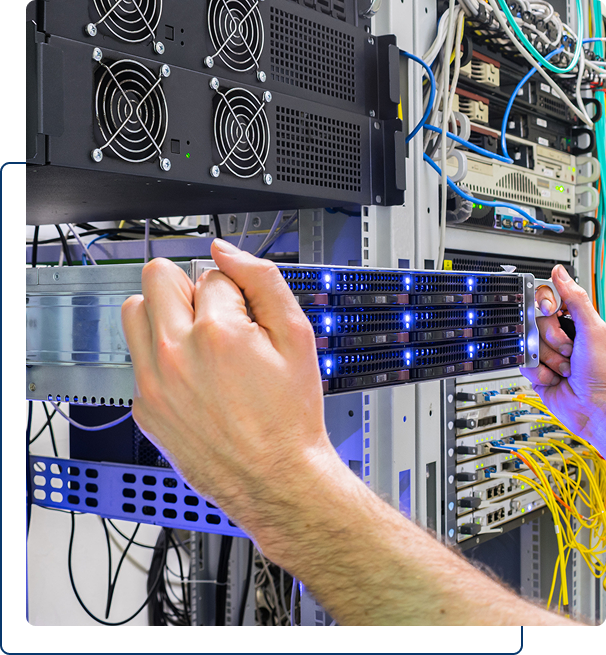 Hands installing or removing a server rack unit in a data center, surrounded by network cables and equipment.