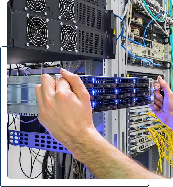 Hands installing or removing a server rack unit in a data center, surrounded by network cables and equipment.